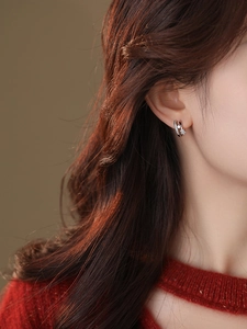 Close-up of star-shaped zircon earrings worn by a model in a warm-toned setting