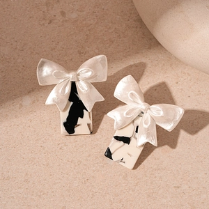 Vintage resin bow earrings with black and white marbled rectangle drops on stone background