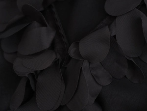 Detailed close-up of 3D floral appliqués and textured fabric on a black V-neck shirt