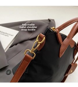 Close-up of golden metal buckle on black nylon tote bag with adjustable shoulder strap