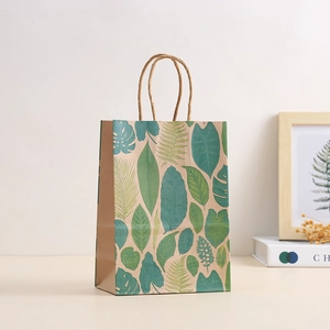 Detail of kraft paper gift bag with green tropical leaf prints and woven paper handles