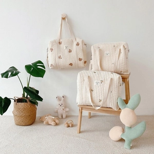 Detailed embroidery of bear and olive branches on quilted cotton mommy bags in cream finish