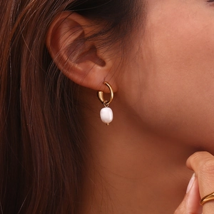 Close-up of 18K gold plated hoop earring with a white freshwater pearl pendant on ear