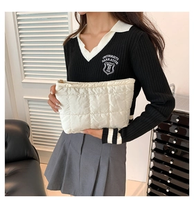 Detail of white quilted nylon clutch bag showing puffy texture and metal zipper