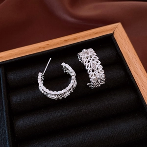 Detailed macro view of silver hollow leaf earrings set with cubic zirconia in jewelry box