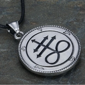 Silver satanic ram head medallion pendant with black rope on grey stone background