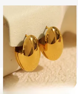 Detailaufnahme polierter goldener Tropfenohrringe mit glänzender Metallic-Spiegeloberfläche