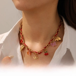 Detail of red woven rope necklace with gold chain and mixed colorful sun and heart charms