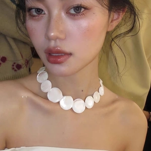Close-up of a white shell choker necklace with large iridescent round mother of pearl discs