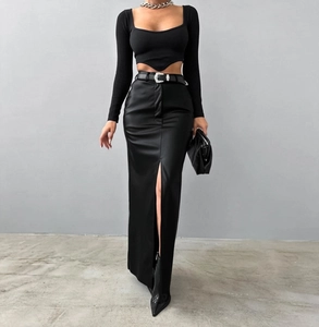Detail of high-waisted black leather skirt with side slit and silver buckle belt