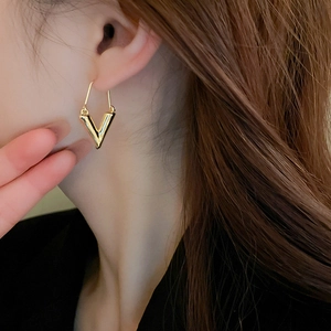 Gros plan de boucles d'oreilles dorées en forme de V portées par un mannequin