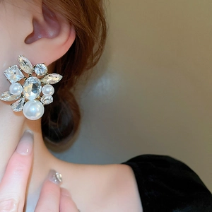 Detail of vintage flower earrings with pearls and oval crystals worn by a model