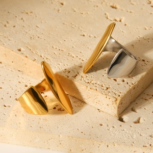 Minimalist gold and silver geometric steel rings displayed on a textured stone surface