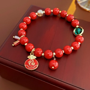 Vue détaillée du bracelet de perles rouges avec breloque dorée Fu sur boîte en bois