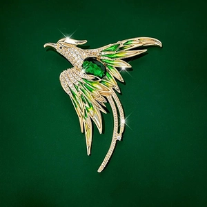 Exquisite enamel phoenix brooch with green gemstones and gold-plated details on dark background
