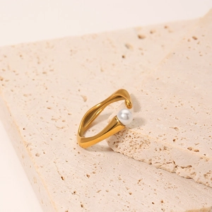 Irregular 18k gold wave ring with pearl accent on a minimalist stone display pedestal