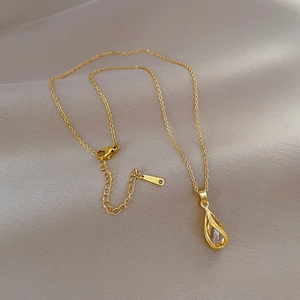 Gold stainless steel necklace with crystal inside teardrop pendant on soft fabric