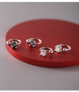 Macro shot of 925 sterling silver ear cuffs with clear and black zircon studs on a red base