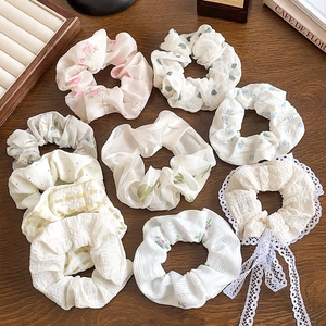 Assorted floral lace scrunchies with ribbons in soft pastel colors on wooden surface