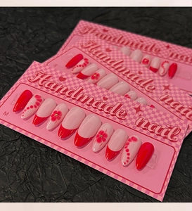 Macro view of handmade almond press-on nails with red French tips and floral designs