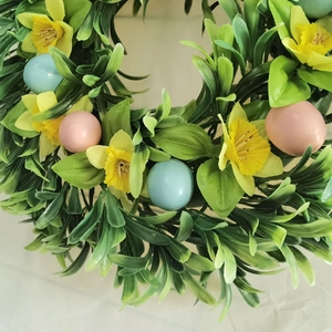 Easter wreath with yellow daffodils and macaron colored eggs on a white background