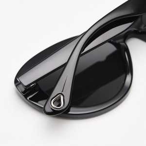 Detail of black cat-eye sunglasses featuring silver teardrop metal inlay on the temple tip