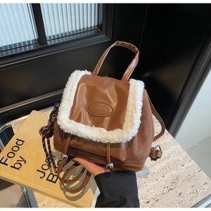 Detail of brown leather and suede mini backpack with white faux shearling trim accents