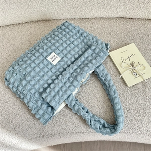 Detail of the light blue bubble textured canvas tote bag with a woven brand label