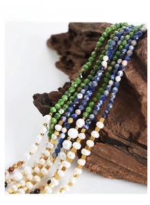 Detail of multi-strand necklace with natural green stones and freshwater pearls on wood