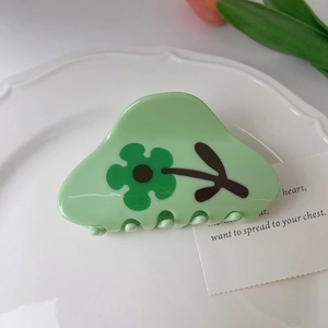 Detail of light green tulip flower hair claw clip on white ceramic plate with soft light