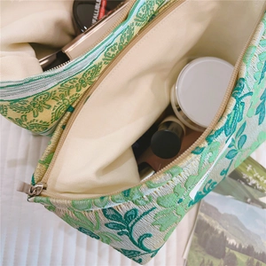 Close-up of green floral jacquard makeup bag interior with metal zipper detail