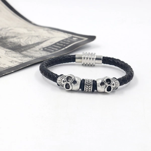 Detail of black braided leather men's bracelet with silver skull beads and magnetic clasp