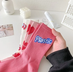 Detailed close-up of pink mid-calf socks featuring embroidered letters and red heart patterns