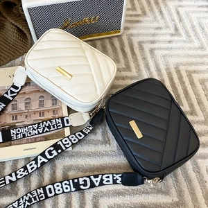 Detail of quilted PU leather camera bags in black and white with wide woven straps