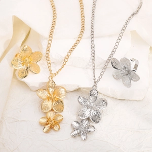 Floral jewelry set with gold and silver necklaces and rings on marble stand