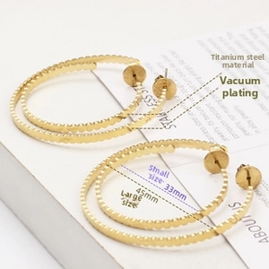 Macro shot of 18k gold plated titanium steel hoop earrings with textured beaded edges