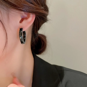 Gros plan d'un mannequin portant des boucles d'oreilles en zircon noir au style vintage