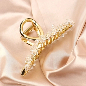 Detail of golden metal hair claw clip featuring natural amethyst crystals on satin