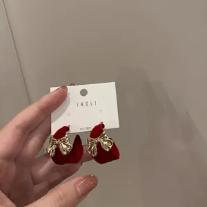 Detailed macro view of festive red velvet earrings with gold metal bow and S925 silver pin