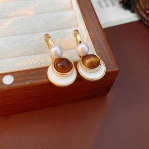 Detailed view of vintage gold earrings with amber resin stone and white pearl accents