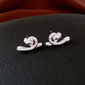Macro detail of silver abstract fluid wave earrings with shiny metallic texture on black fabric