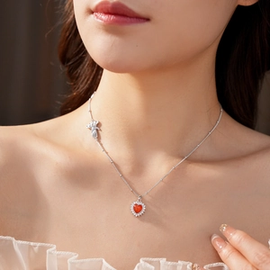 Detail of red heart pendant necklace with micro-pave diamonds and hand charm on a silver chain