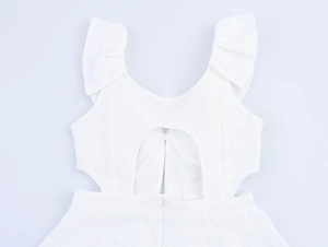 Detail of white maxi dress featuring ruffled straps, cut-out back and floral jacquard fabric