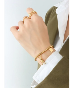 Detail eines 18k vergoldeten Armbands mit Hasenanhänger und stapelbarem Ringset