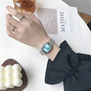 Elegant women's watch with blue square dial and silver mesh strap on model's wrist