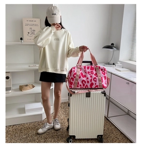 Pink leopard print travel bag placed on a white suitcase for a modern travel style