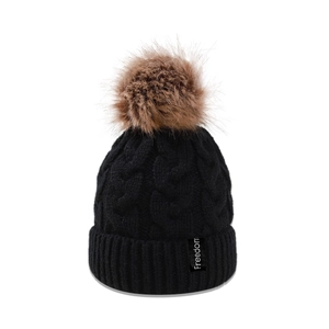 Détail du bonnet en maille torsadée noire avec pompon en fausse fourrure marron