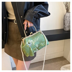 Close-up of green embroidery shell bag with pearl handle and silk tassel detail