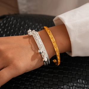Bracelet manchette géométrique plaqué or 24K et gourmette argentée portés par un modèle
