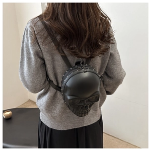 Detail view of 3D skull backpack in black PU leather with studs on a fashion model